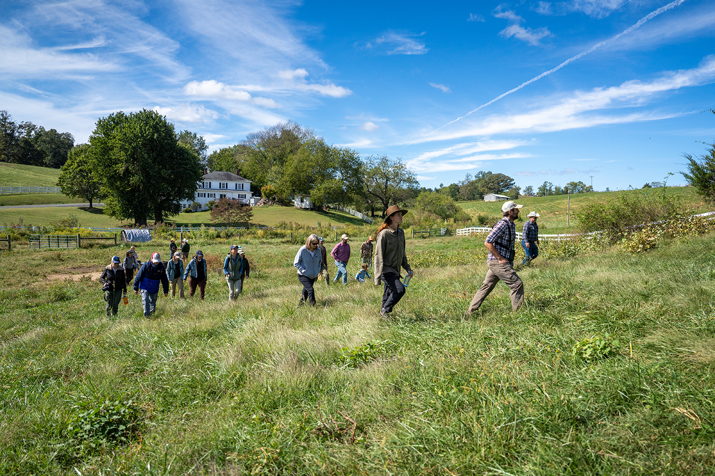 a group of folks walk across a farm fields