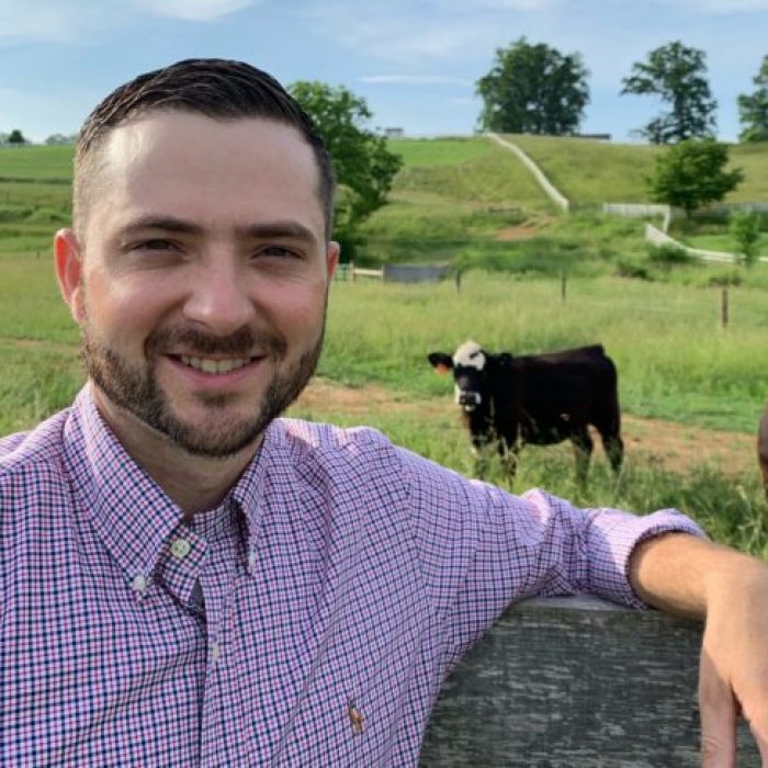 Jacob-e1559572001840-scaled portrait image of a man with a field and cow in the background